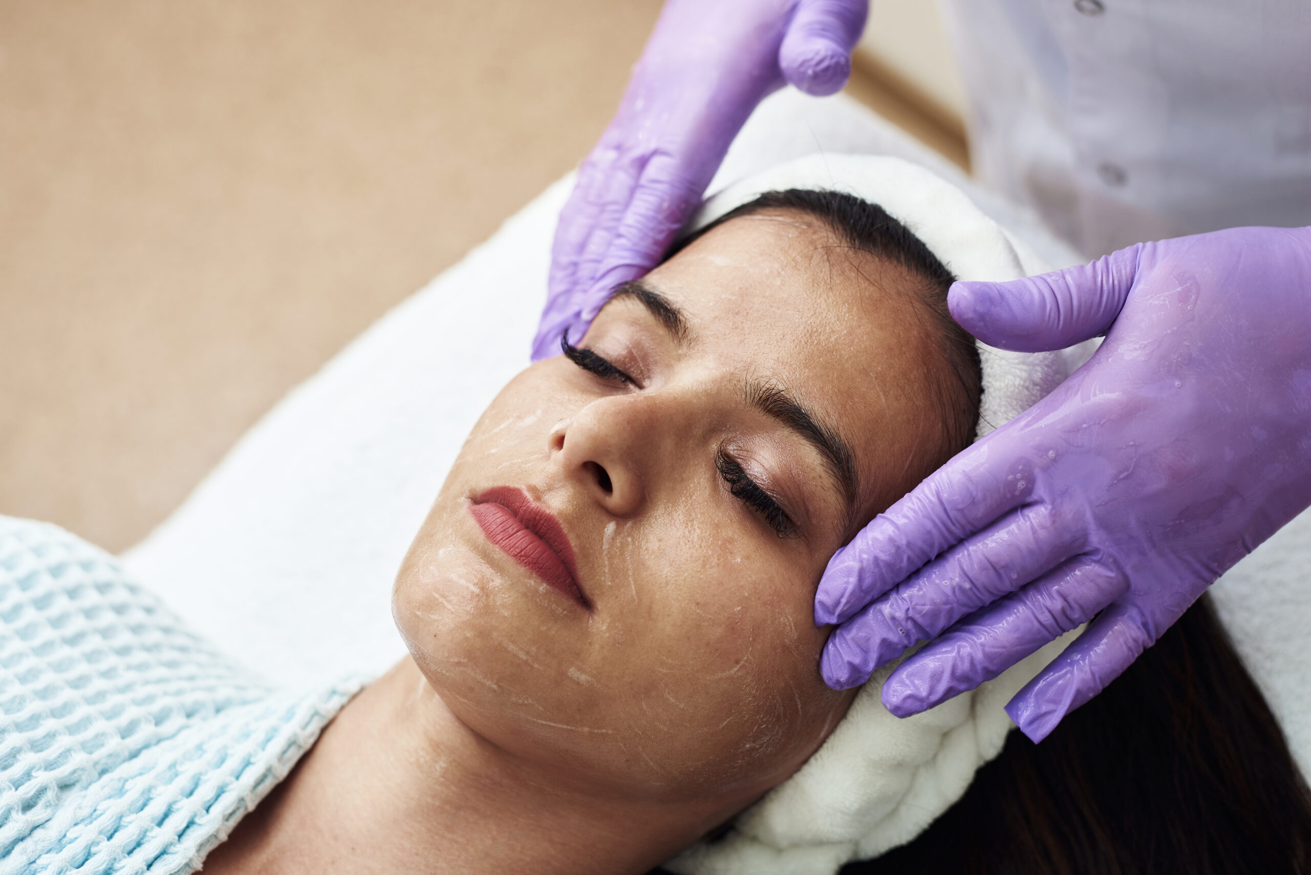 A beautiful young woman enjoys a toning facial massage. The concept of spa treatments, skin care and anti-aging