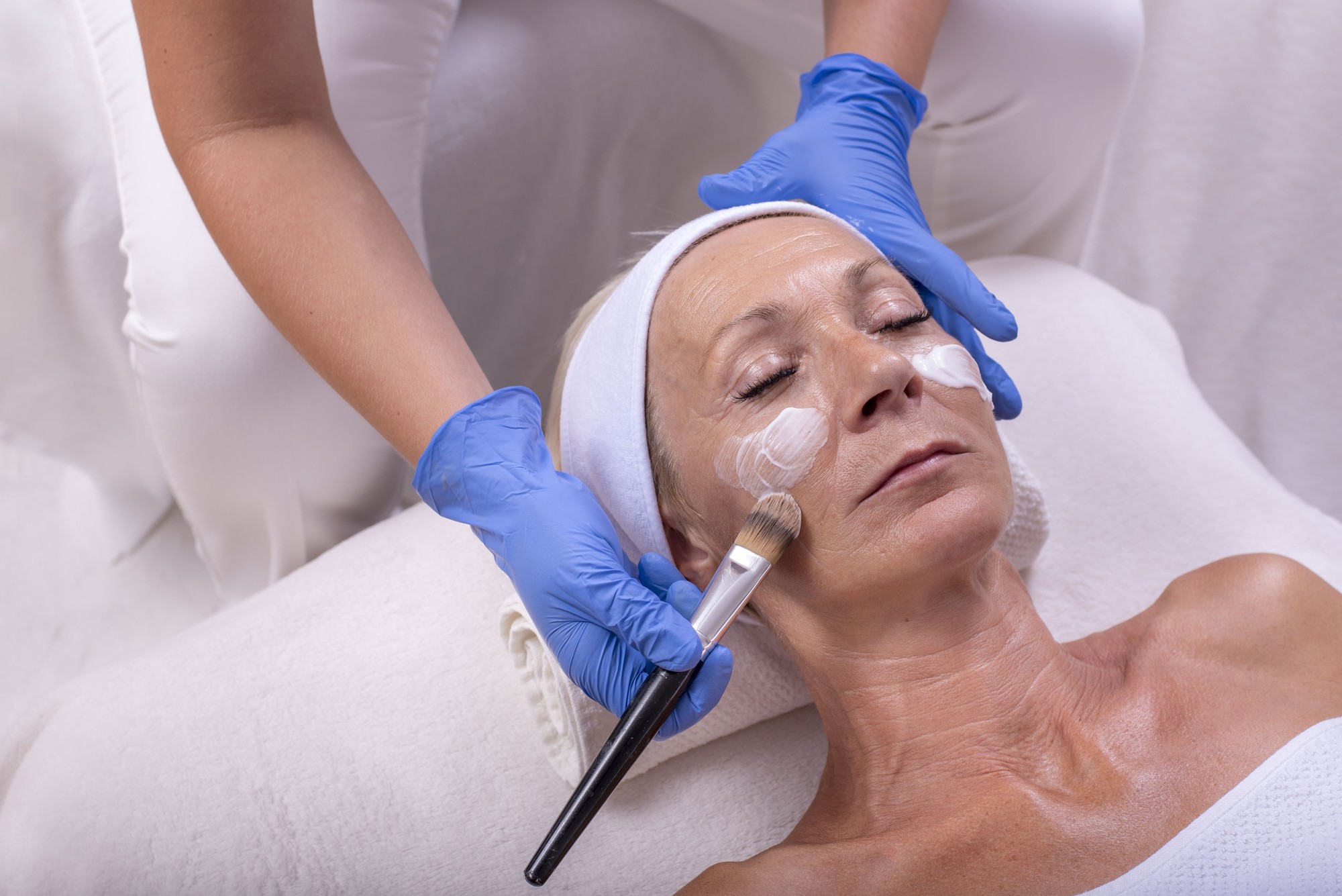 closeup-caucasian-senior-woman-applying-face-cream-beauty-salon